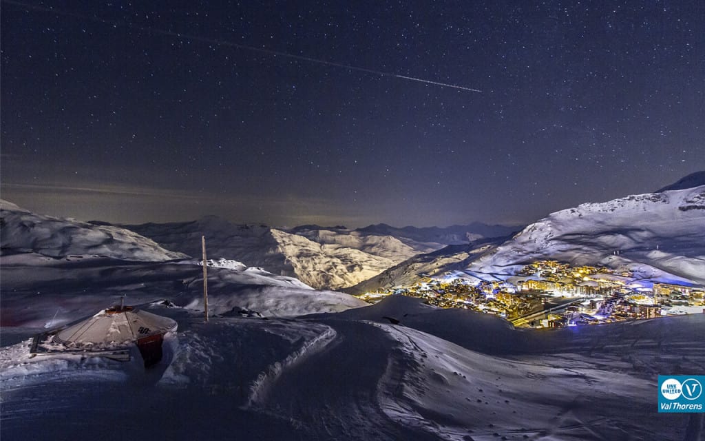 val thorens village and mountain at night with stars and shooting star