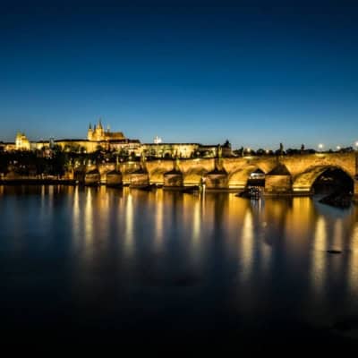 classic prague photograph of the charles bridge lit up at night