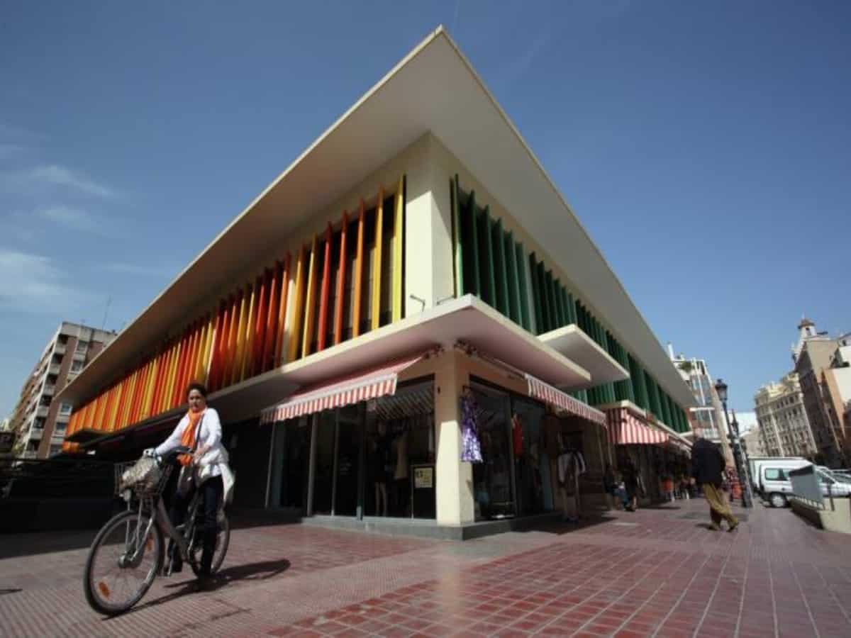 person riding bike in front of colorful building in ruzafa neighborhood