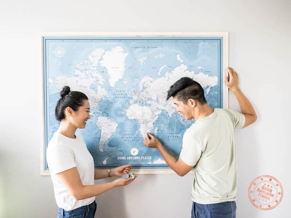 asian couple having fun with world map with pins by pin adventure map