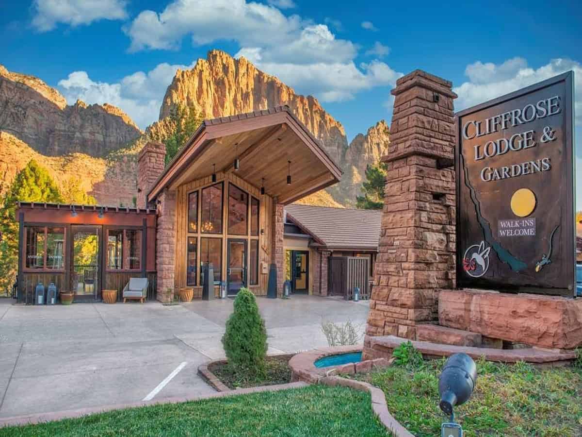 exterior of cliffrose hotel with sign in front of cliffs
