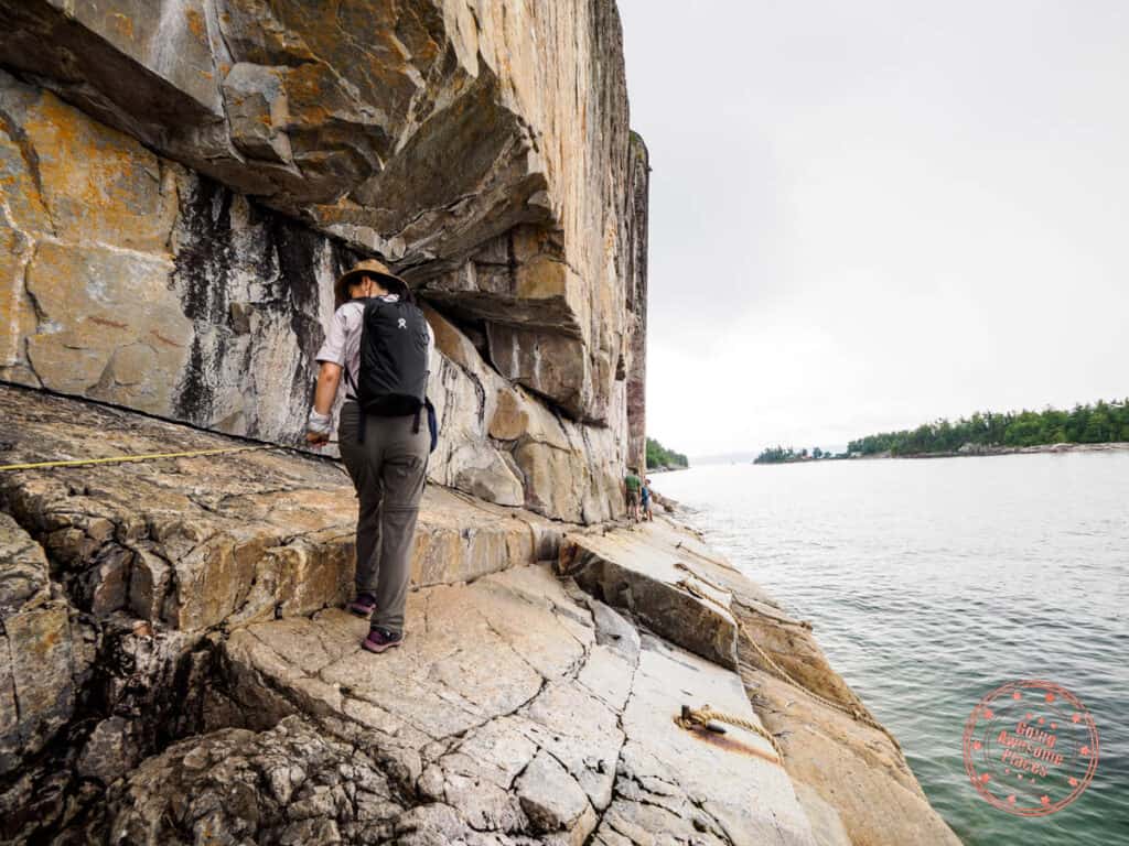 holding onto rope and chain to avoid slipping to see the agawa rock pictographs near sault ste marie