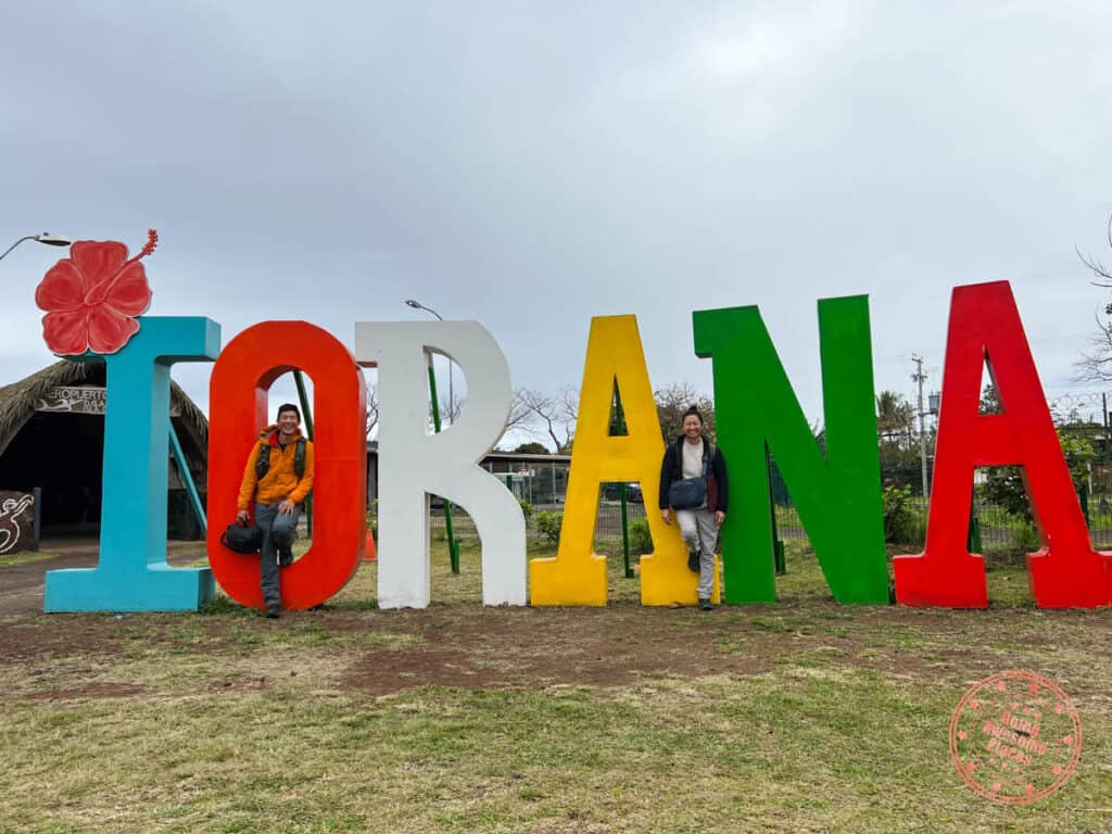 couple standing in front of iorana sign in how to get to easter island