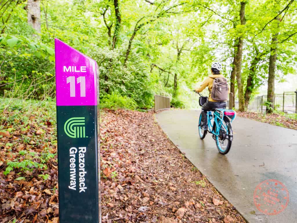 biking by mile marker on razoback greeway trail near fayetteville