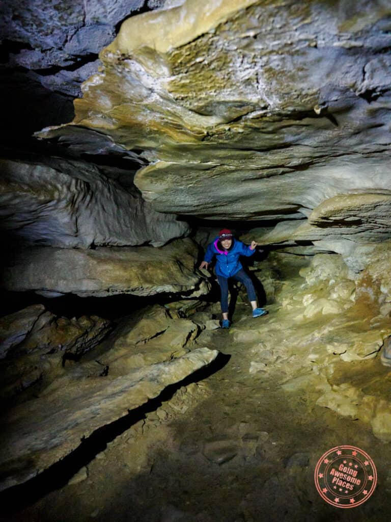 woman navigating tight passageways of eden falls cave on lost valley trail