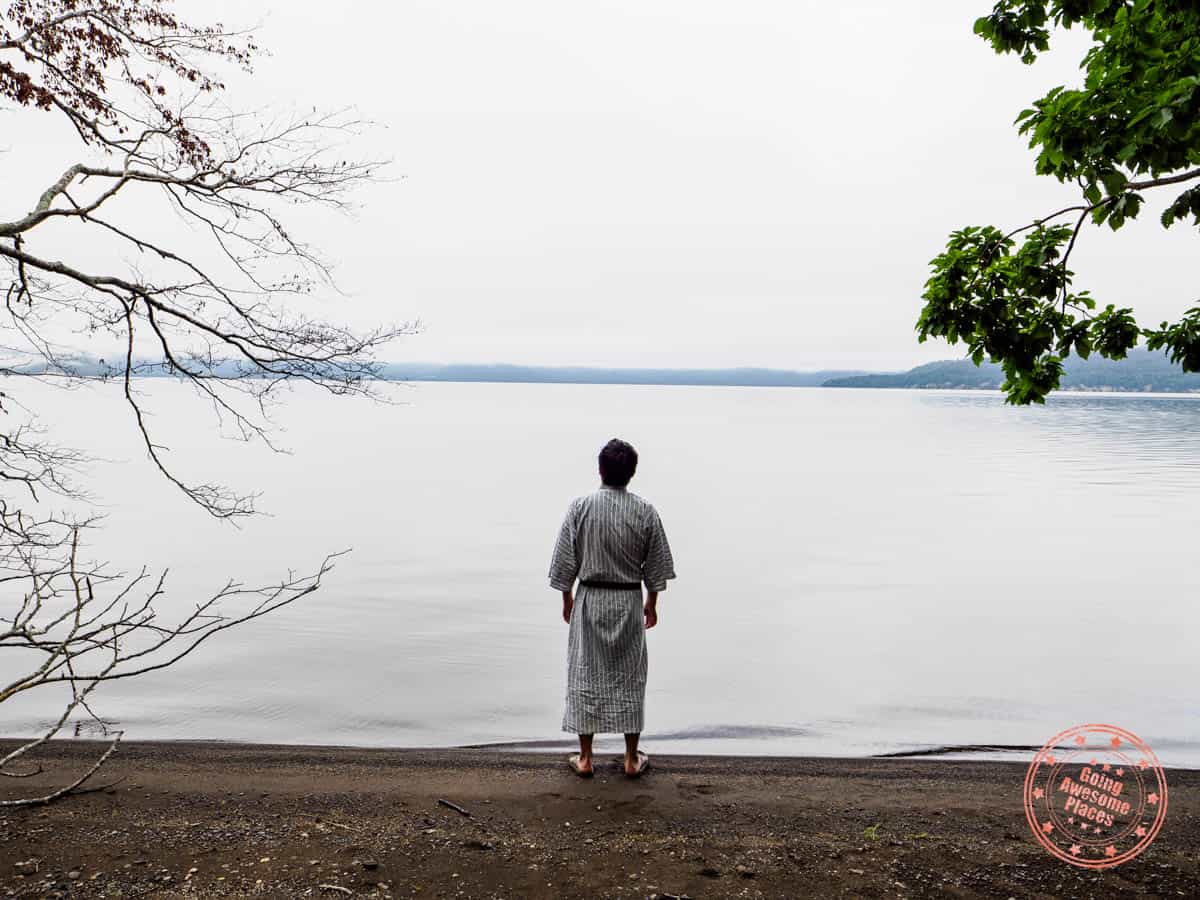 man enjoying lake kusshari early in the morning across from gasthof papilio while wearing a yukata 