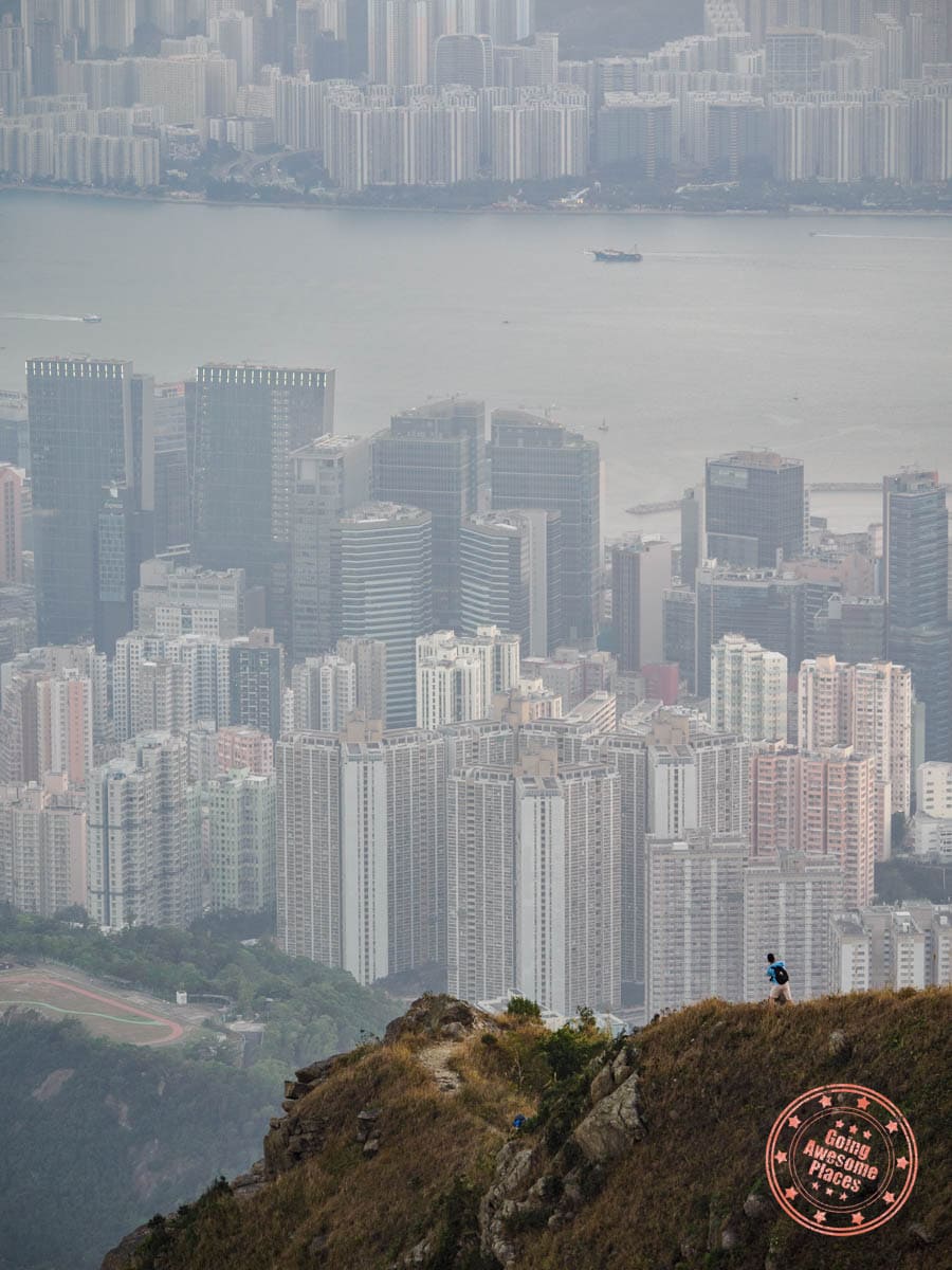 dramatic separation of kowloon peak hike trail that falls towards suicide cliff and city skyscrapers behind