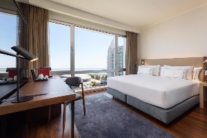 melia lisboa oriente hotel room with bed, desk and window with view