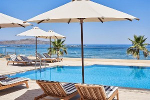 atlantica kalliston resort lounge chairs under umbrella poolside oceanview