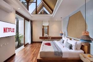 sanora villa sanur room with flower message on king bed, glass slidong doors, ceiling windows above bed