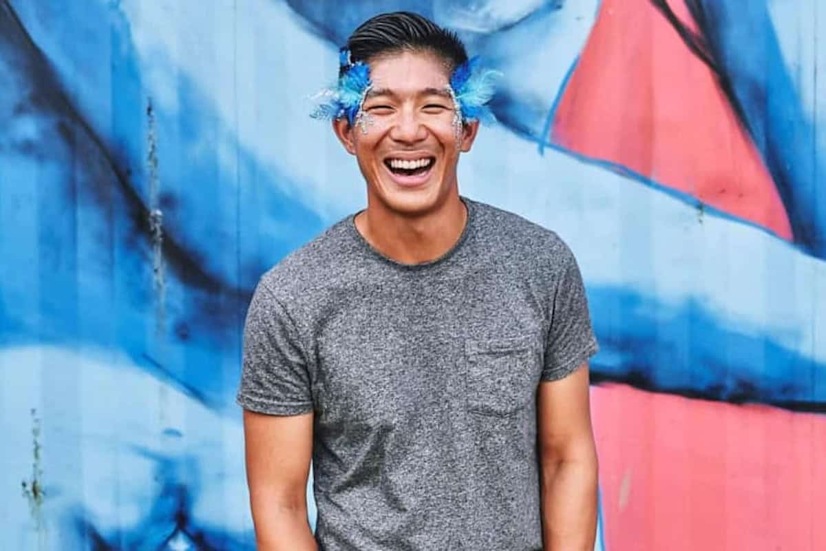 William Tang in front of a blue a red wall.