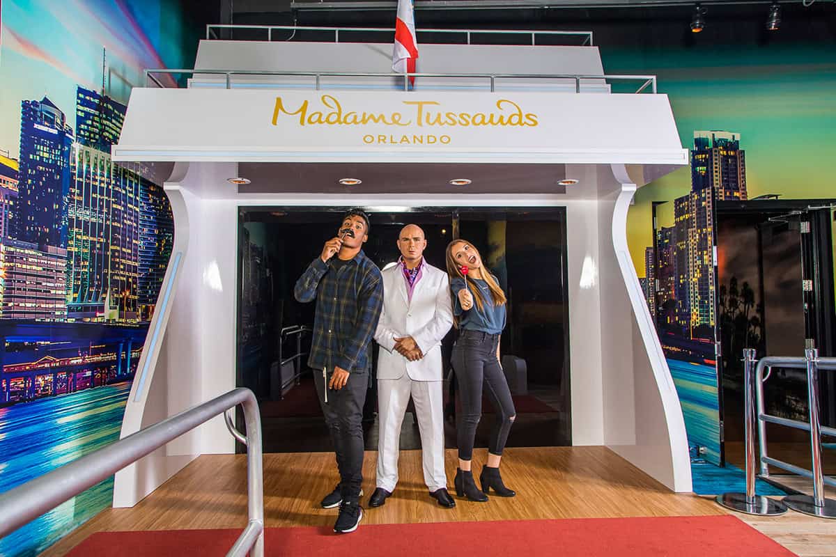 tourists posing with pitbull wax figurine at madame tussauds