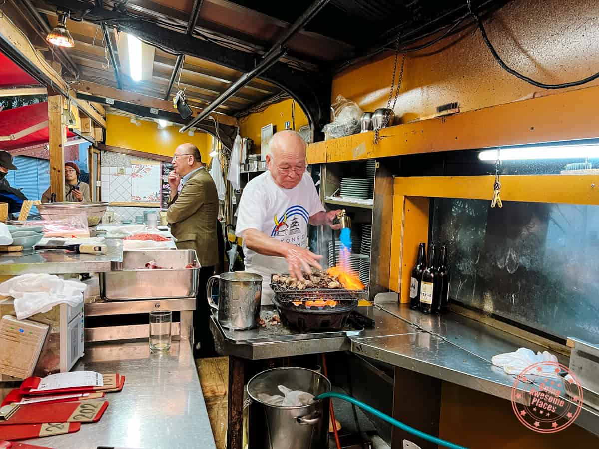 10 Day Japan Itinerary For First Timers - Modern Golden Route izakaya toyo in osaka running his hands through the tuna cheeks with the flamethrower on