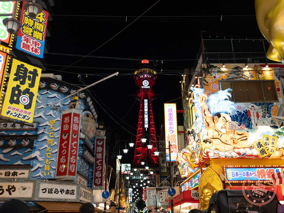 tsutenkaku tower lit up at night amongst other buildings
