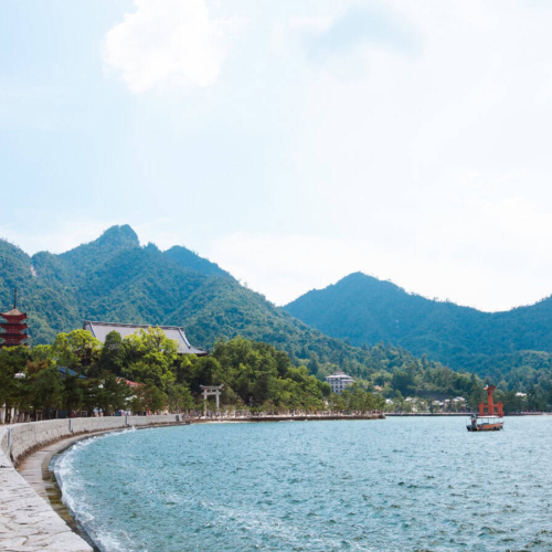 torri gate in water and mountains in the distance of miyajima island