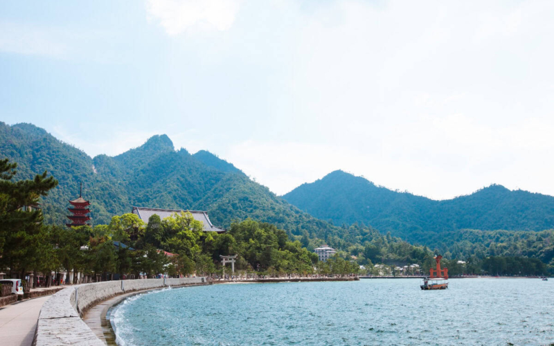 torri gate in water and mountains in the distance of miyajima island