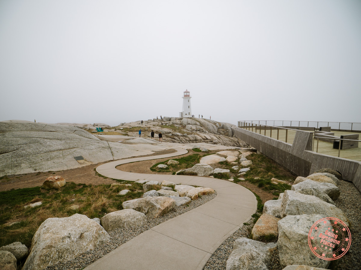 peggy's cove lighthouse with concrete path leading towards it and the viewing deck to its right
