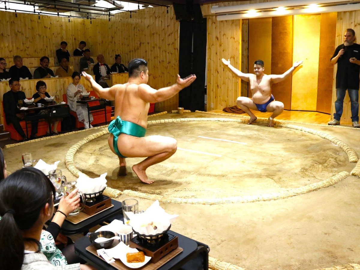 people enjoying their chicken hot pot while watching a sumo show