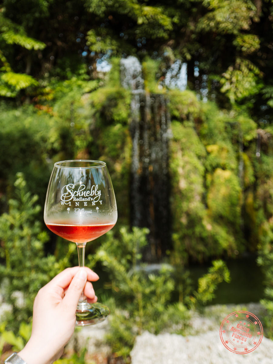 holding schenbly's winery wine glass with waterfall behind