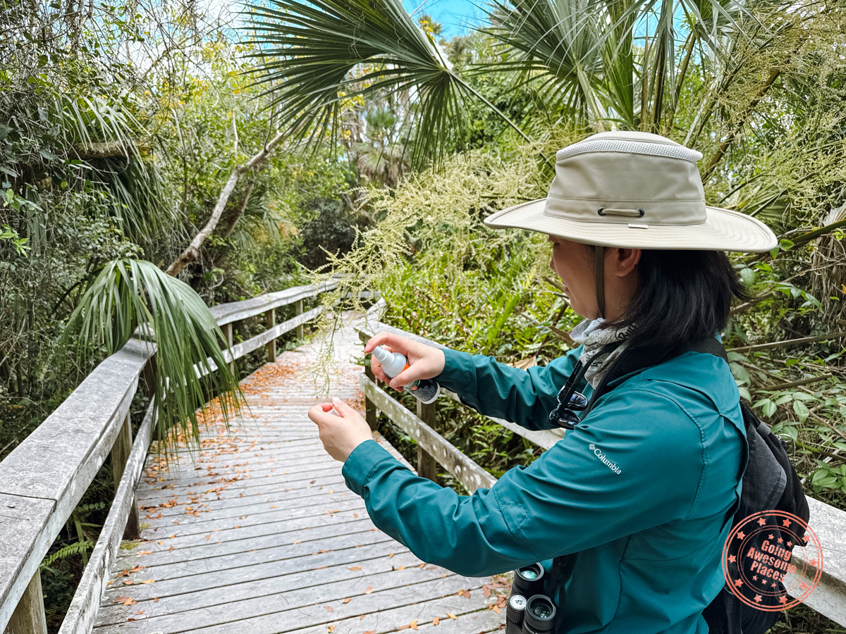 asian woman spraying mosquito repellent in everglades national park